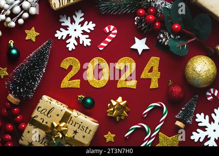 Frohes neues Jahr 2024. weihnachtsschmuck von oben und goldene Zahlen mit der Zahl 2024 auf rotem Hintergrund. Silvesterfeier Konzept Backgr Stockfoto