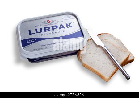 Lurpak streichbare Butter im Einzelhandelsbehälter mit zwei Brotscheiben und isoliertem Schneidebrot auf weiß Stockfoto