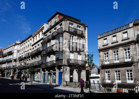 Mann, der an typischen Granitsteingebäuden mit schmiedeeisernen Balkonen und Fenstern vorbeiläuft, Vigo, Galicien, Nordwesten Spaniens Stockfoto