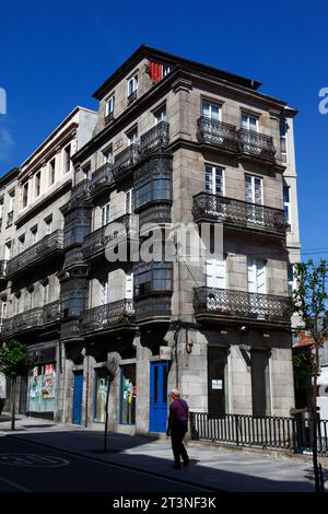 Mann, der an typischen Granitsteingebäuden mit schmiedeeisernen Balkonen und Fenstern vorbeiläuft, Vigo, Galicien, Nordwesten Spaniens Stockfoto