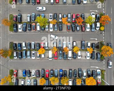 26. Oktober 2023, Sachsen, Leipzig: Einige herbstfarbene Bäume sorgen für Farbtupfer auf dem Parkplatz eines Einkaufszentrums. Der Herbst wird in den nächsten Tagen feucht, kalt und unangenehm bleiben. (Mit einer Drohne aufgenommen) Foto: Jan Woitas/dpa Stockfoto