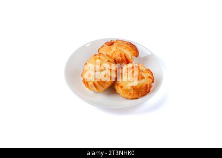 Goldene Profiterolen gefüllt mit Creme, serviert auf weißem Teller isoliert auf weißem Hintergrund. Stockfoto