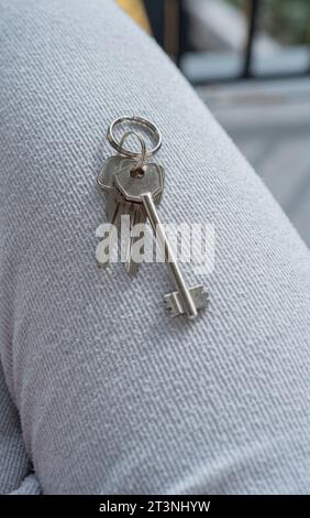 Eine junge Frau, die zu Hause den Schlüssel eines neuen Hauses hält. Nahaufnahme der Schlüssel aus dem neuen Haus Stockfoto