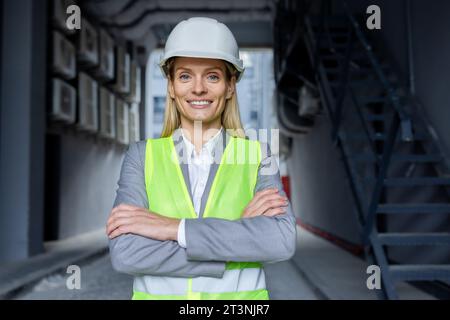 Porträt einer erfahrenen, erfolgreichen Ingenieurin, Arbeiterin in Schutzhelm und reflektierender Weste mit überkreuzten Armen, die lächeln und in die Kamera schauen. Stockfoto