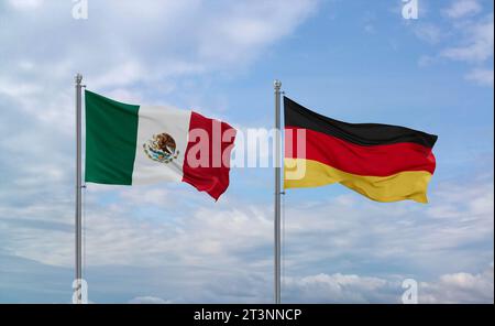 Deutschland und Mexiko-Flaggen schwenken zusammen auf blauem bewölktem Himmel, zwei Länder-Beziehungskonzept Stockfoto