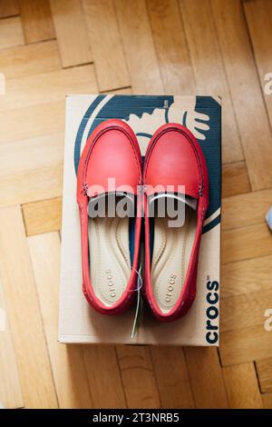 Paris, Frankreich - 18. Oktober 2015: Ein Paar leuchtend roter Crocs-Schuhe auf einer Crocs-Box vor einem Holzboden Stockfoto