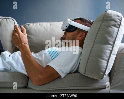 Mann, der eine Virtual-Reality-Brille verwendet, ein vr-Headset der neuen Generation auf dem Sofa trägt. Stockfoto