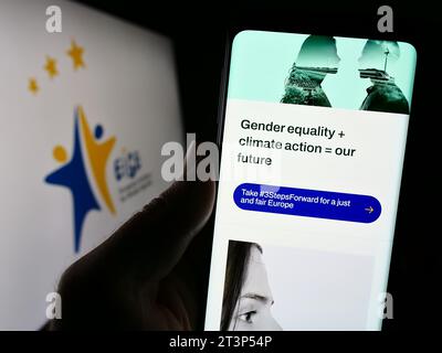 Person mit Smartphone und Website des Europäischen Instituts für Gleichstellungsfragen (EIGE) vor dem Logo. Konzentrieren Sie sich auf die Mitte des Telefondisplays. Stockfoto