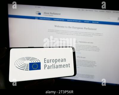 Person, die ein Mobiltelefon mit dem Logo des EU-Legislativorgans des Europäischen Parlaments (EP) vor der Webseite hält. Schwerpunkt auf dem Display des Telefons. Stockfoto