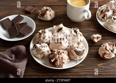 Hausgemachte Schokoladen-Meringue-Kekse und eine Tasse Kaffee auf Holztisch. Nahansicht Stockfoto