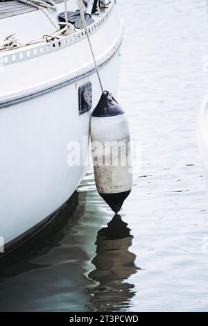 Schwimmboje hängt an einem kleinen Boot im Hafen Stockfoto