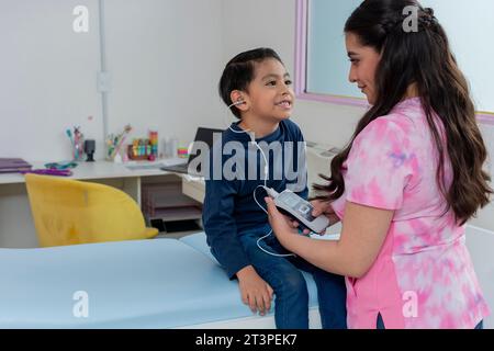 Arzt, der ein Hörscreening an einem Kind in ihrer Kinderpraxis durchführt. Höruntersuchung für ein Kind. Kopierbereich Stockfoto