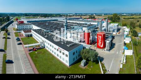 Staniątki, Polen – 9. September 2023: Coca Cola-Fabrik in der Nähe von Krakau in Polen. Große Produktionsanlage. Tolle Gebäude und große rote Container mit gratis Stockfoto