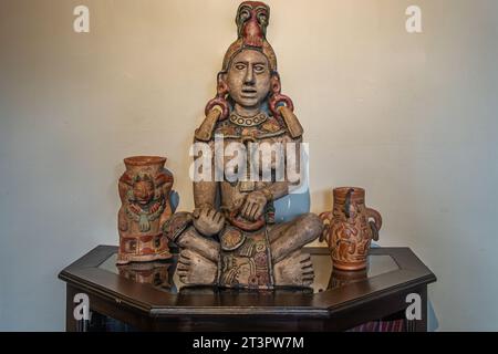 Guatemala, La Antigua - 20. Juli 2023: Jade Maya Museum. Nahaufnahme. Ixchel, Maya-Fruchtbarkeit und Mondgöttin-Statue auf dunklem Holzschrank, plus 2 kleine Stockfoto