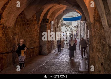 Die Touristen gehen durch dunkle Bögen in der Altstadt von Jerusalem in Jerusalem, Israel. Stockfoto