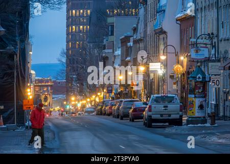 Ein Fußgänger überquert die Straße an einem Winterabend in Old Quebec, Quebec City, Provinz Quebec, Kanada. Wir können Chateau Frontenac oben sehen Stockfoto