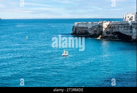 Menschen in einem kleinen Boot im klaren Wasser der Adria, in der Nähe des Strandes Cala Ponte in Polignano a Mare, Italien, Stockfoto