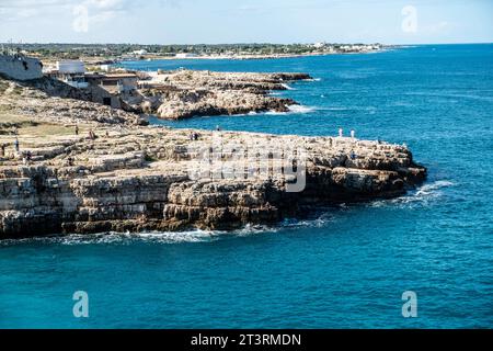 Der Felsvorsprung gegenüber dem Strand Cala Ponte in Polignano a Mare, Italien, umgeben vom kristallklaren Wasser der Adria. Stockfoto