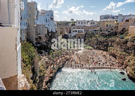 Menschen genießen den Strand Cala Ponte in Polignano a Mare, Italien, an einem sonnigen Sonntagnachmittag im Oktober. Stockfoto