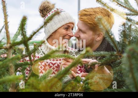 Verliebtes Paar kauft weihnachtsbaum auf dem Straßenmarkt Stockfoto