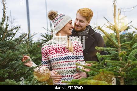 Glückliches Paar, das sich verliebt hat, am Abend weihnachtsbaum auf dem Straßenmarkt zu kaufen. Winterferien und Menschen Konzept Bild Stockfoto