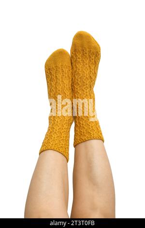 Weibliche Beine in gelben handgestrickten Wollsocken isoliert auf weißem Hintergrund, Schnittpfad inbegriffen Stockfoto