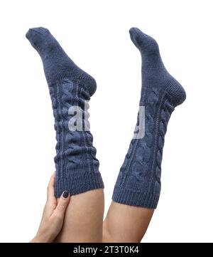 Weibliche Beine in dunkelblauen handgestrickten Kniestrümpfen aus Wolle isoliert auf weißem Hintergrund, Schneidepfad inbegriffen Stockfoto