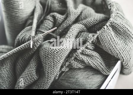 Projekt wird zusammengefügt. Ein Stück Stricken mit Garnknäueln und einer Stricknadeln Nahaufnahme Stockfoto