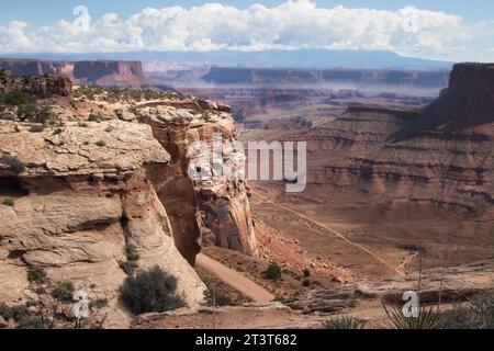 Rising Butte, Canyon Floor, Foggy Horizon: A Rising butte scheint sich für eine unbefestigte Straße zu trennen, die zum Canyon Floor im Canyonlands National Park führt Stockfoto