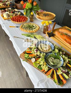 Blick aus einem hohen Winkel auf Räucherlachs, Gemüse mit Bohnen-Dip und verschiedene Torten auf der Veranda Stockfoto