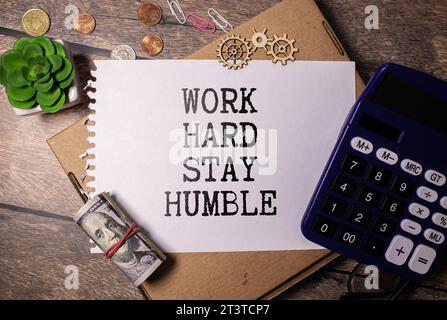 Zitate von ARBEIT HART BLEIBEN BESCHEIDEN auf bunten Notizpapieren mit hölzernem Hintergrund. Stockfoto