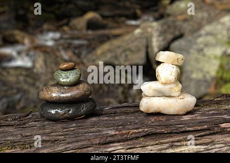 Zwei Stapel dunklerer und hellerer Steine auf einem gefallenen Baumstamm in Nord-Idaho. Stockfoto