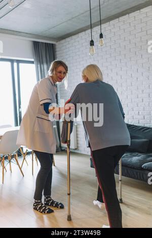 Frau, die mit dem Altersheim der Krankenschwester läuft Stockfoto