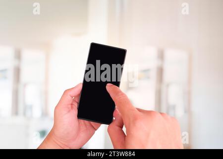 Nahaufnahme von Händen, die das Smartphone halten, mit leerem Bildschirm über verschwommenem Hintergrund Stockfoto
