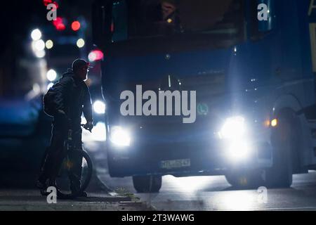 Leipzig, Deutschland. Oktober 2023. Ein abbiegender Lkw fährt in der Nähe eines Radfahrers vorbei, der darauf wartet, die Straße zu überqueren. Quelle: Jan Woitas/dpa/Alamy Live News Stockfoto