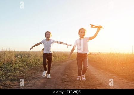 Fröhliche Schwestern laufen auf der Straße und spielen mit dem Flugzeug Stockfoto