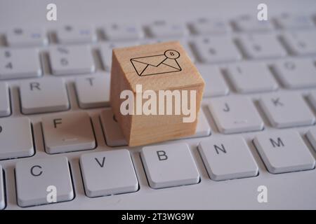 Holzwürfel mit neuem E-Mail-Benachrichtigungssymbol oben auf der Tastatur. Kommunikations- und Technologiekonzept Stockfoto