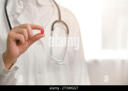 Ergänzungen für ein stärkeres Immunsystem. Nahaufnahme einer jungen Ärztin mit einer roten Einzelpille, einer Krankenschwester mit weißem Mantel und Stethoskop. Mittel Stockfoto