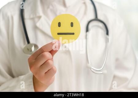 Nahaufnahme einer jungen Ärztin in Uniform mit Stethoskop mit gelbem traurigem Gesicht, schlechtes Emoticon. Feedback-Bewertung und Kundenrezension, Erfahrung, Sat Stockfoto