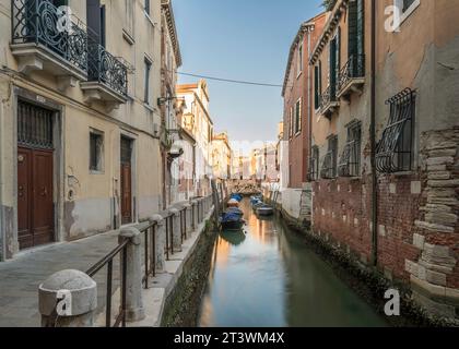 Typisch venezianischer Kanal, früh am Morgen. Venedig, Italien. Die Gebäude spiegeln sich auf dem ruhigen Wasser Stockfoto