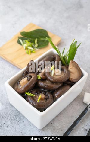 Appetitliche marinierte Shiitake-Pilze in einer Salatschüssel auf einem Holztisch... Marinierte Shiitake-Pilze, verzehrfertig. Stockfoto