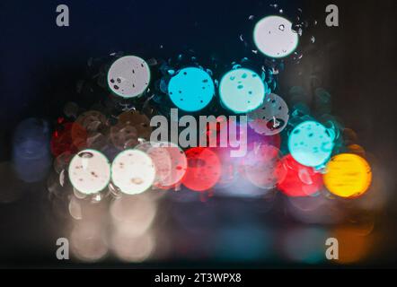 Leipzig, Deutschland. Oktober 2023. Die Lichter im Straßenverkehr ziehen bunte Punkte auf eine nasse Windschutzscheibe. Quelle: Jan Woitas/dpa/Alamy Live News Stockfoto