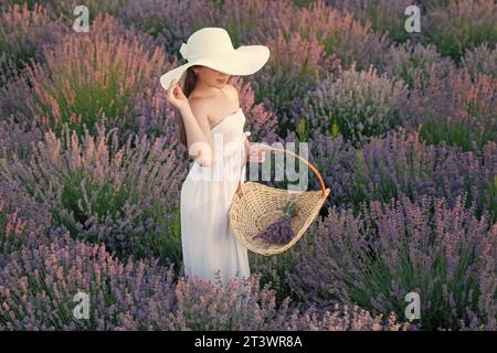 Teenager mit Lavendel auf der Wiese. Teenager-Mädchen mit Lavendelblume, die auf dem Feld steht. Teenager mit Lavendel und Blumenstrauß. Teenager-Mädchen Stockfoto