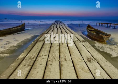 Holzponton mit Booten vor Sonnenaufgang im Donaudelta Stockfoto