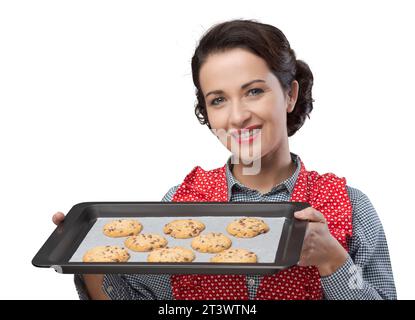 Lächelnde Vintage Frau bereitet köstliche Kekse serviert auf einem Backblech Stockfoto