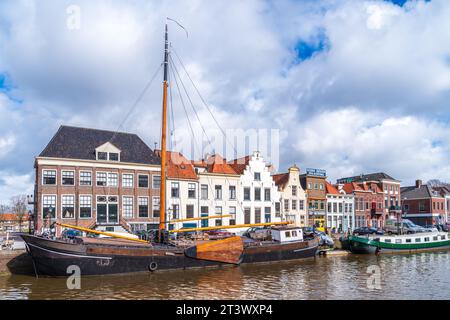 ZWOLLE, NIEDERLANDE - 14. MÄRZ 2021: Alte Boote und Lastkähne vor einigen schönen Giebelhäusern in der niederländischen Stadt Zwolle Stockfoto