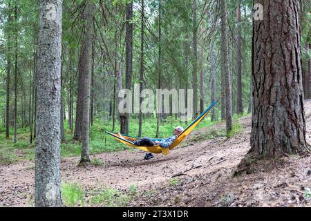 Ein Mann, Tourist, entspannend in einer Hängematte in einem Wald in Estland, genießt beim Wandern und Camping in der estnischen Wildnis, Estland, Europa Stockfoto