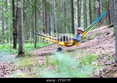 Ein Mann, Tourist, entspannend in einer Hängematte in einem Wald in Estland, genießt beim Wandern und Camping in der estnischen Wildnis, Estland, Europa Stockfoto