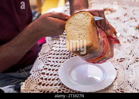 Ein Mann hält Stücke von geschnittenem Brot vor dem Frühstück in der Hand Stockfoto