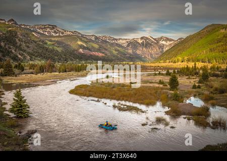 Mann, der ein kleines Schlauchboot in einem Fluss in den Bergen paddelt. Stockfoto